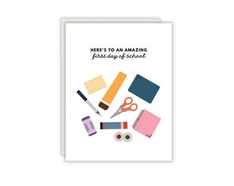Könnte beinhalten: Eine weiße Grußkarte mit dem schwarzen Text "HERE'S TO AN AMAZING first day of school". Unter dem Text befinden sich bunte Illustrationen von Schulbedarf, darunter ein Stift, ein Bleistift, eine Schere, ein rosa Spiralblock und ein Radiergummi.