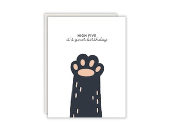 Könnte beinhalten: Eine weiße Grußkarte mit einer dunkelblauen Tierpfoten-Illustration und hellrosa Ballen. Der Text oben lautet HIGH FIVE it's your birthday in schwarzer und dunkelblauer Schrift. Die Karte ist rechteckig und hat ein schlichtes Design.
