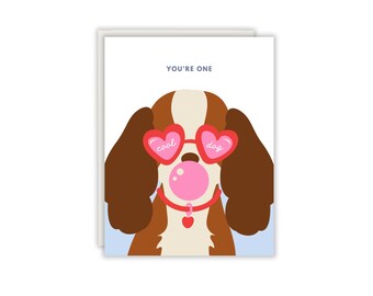 Könnte beinhalten: Eine Grußkarte mit einem braun-weißen Hund, der eine rote herzförmige Sonnenbrille mit der Aufschrift 'cool dog' auf den Gläsern trägt. Der Hund hat eine rosa Kaugummiblase im Mund und trägt ein rotes Halsband mit einem herzförmigen Anhänger.