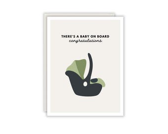 Könnte beinhalten: Eine Grußkarte mit hellbeigem Hintergrund und einer dunkelgrauen sowie salbeigrünen Grafik eines Babysitzes. Der Text oben lautet, THERE'S A BABY ON BOARD congratulations, gedruckt in Schwarz in einer Kombination aus serifenloser und Schreibschrift.