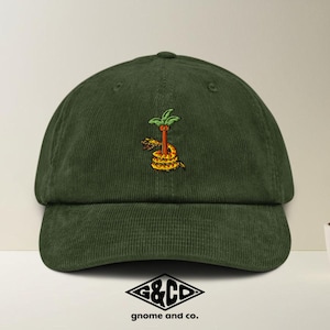 Op de afbeelding: Donkergroene corduroy baseballpet met een geborduurd ontwerp van een palmboom en een slang. De pet heeft een gebogen klep en een gestructureerde kroon. Het logo "G&CO gnome and co." staat onderaan.
