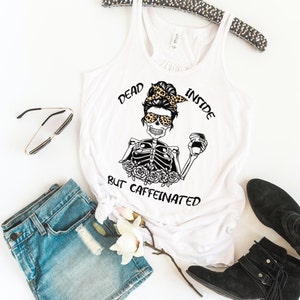 May include: White tank top with a black and white graphic of a skeleton with a coffee cup and the text "Dead Inside But Caffeinated".