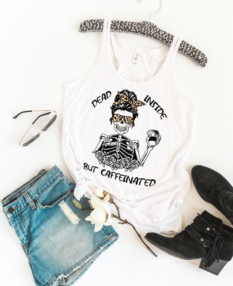 May include: White tank top with a black and white graphic of a skeleton with a coffee cup and the text "Dead Inside But Caffeinated".