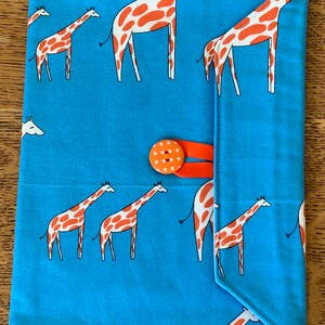 Op de afbeelding: Een blauwe stoffen envelop met een klep sluiting en een knoop. De envelop is versierd met een herhalend patroon van oranje en witte giraffen.
