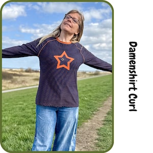 May include: Navy blue long-sleeve shirt with orange trim and a star graphic. The shirt has horizontal stripes and is paired with blue jeans. The text "Damenshirt Curl" is visible in the image.