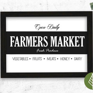 May include: Black and white sign with the text "Open Daily Farmers Market Fresh Produce Vegetables Fruits Meats Honey Dairy" in a white frame.