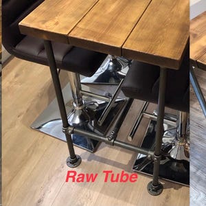 May include: Three wooden tables with different metal leg designs. The table tops are made of stained wood. The legs are made of black, raw, and galvanized metal tubes. The tables are suitable for various interior settings.