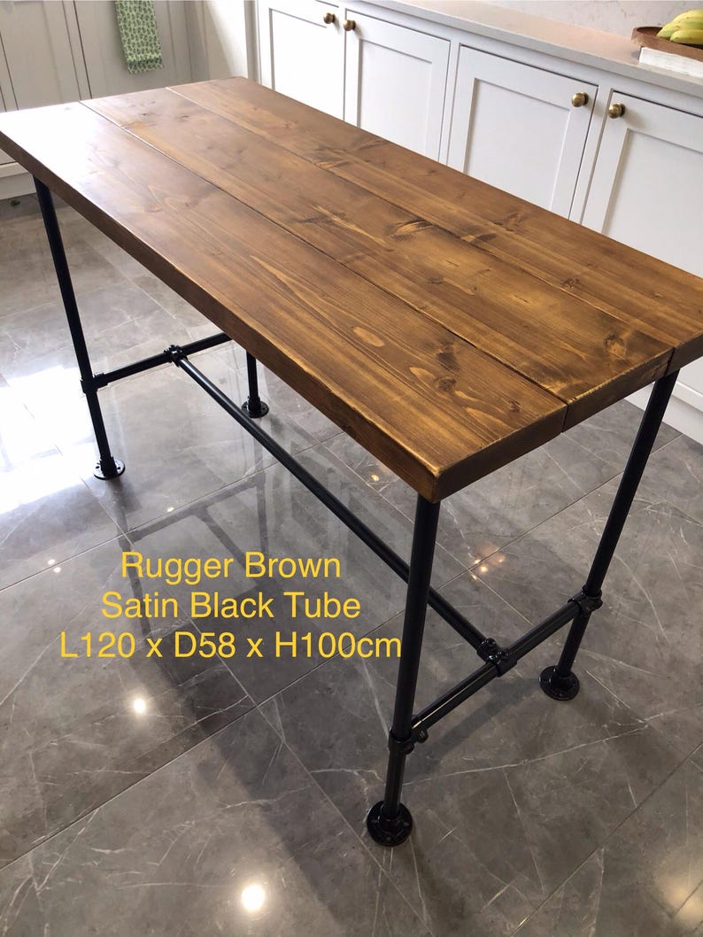 May include: A rectangular table with a Rugger Brown wooden top and black metal pipe legs. The table measures 47.2 inches long, 22.8 inches wide, and 39.4 inches high. The text on the image reads "Rugger Brown Satin Black Tube L120 x D58 x H100cm."