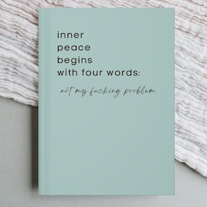 Könnte beinhalten: Ein helltürkises Notizbuch mit dem Text "inner peace begins with four words: not my fucking problem" in Schwarz. Das Notizbuch hat ein schlichtes, modernes Design.