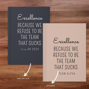 May include: Two notebooks with the text "Excellence BECAUSE WE REFUSE TO BE THE TEAM THAT SUCKS". One notebook is dark gray with "Lina HR 2024", the other is tan with "TEAM ALPHA".