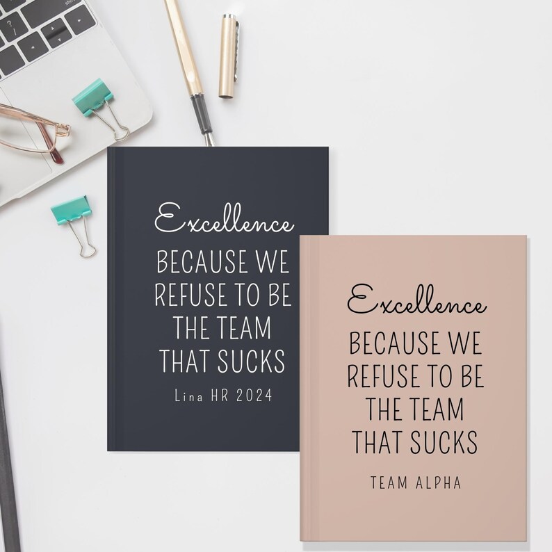May include: Two notebooks with the text "Excellence BECAUSE WE REFUSE TO BE THE TEAM THAT SUCKS". One notebook is navy blue with "Lina HR 2024" and the other is blush with "TEAM ALPHA". A laptop and office supplies are in the background.