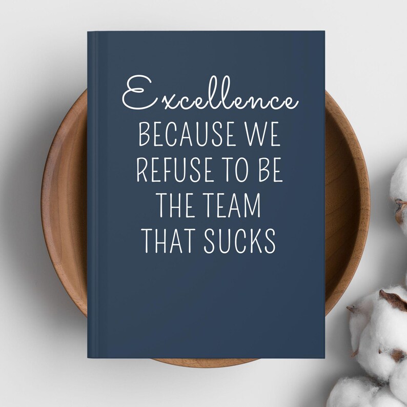 May include: A navy blue notebook with the words "Excellence BECAUSE WE REFUSE TO BE THE TEAM THAT SUCKS" in white script. The notebook is in a wooden bowl, with cotton buds in the background.