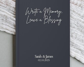 May include: A dark gray hardcover journal with the text "Write a Memory, Leave a Blessing" in white script. The names "Sarah & James" and the date "02.10.2025" are also printed in white.