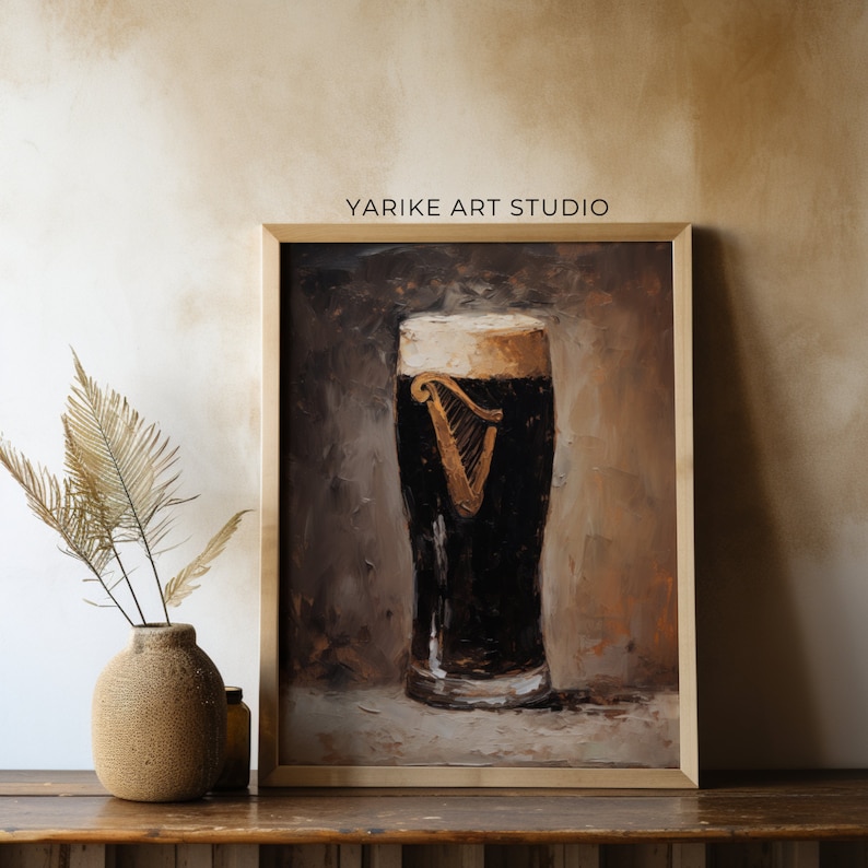 May include: A framed painting depicting a glass of Guinness beer with a white head and the Guinness harp logo. The painting is executed in a brown and beige colour palette and features a textured, brushstroke effect.
