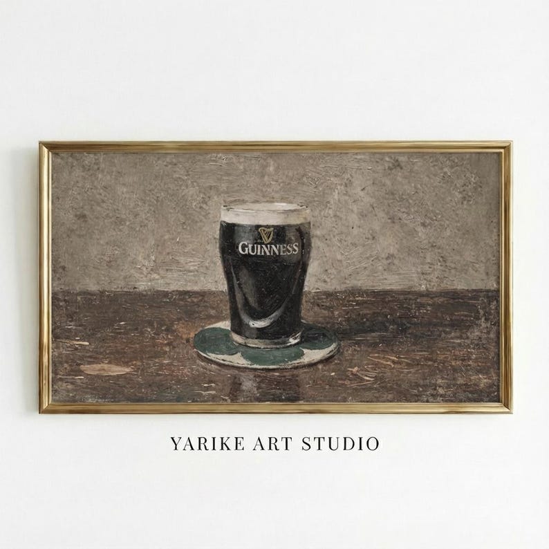 May include: A framed print of a pint of Guinness stout on a green coaster. The glass is filled with dark beer and has the Guinness logo. The artwork is set on a wooden table with a neutral background. The text "YARIKE ART STUDIO" is at the bottom.