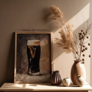 May include: A framed painting depicting a glass of dark beer with a white head. The beer features a gold harp logo. The painting is displayed on a wooden table with a vase of dried flowers and other decorative items.