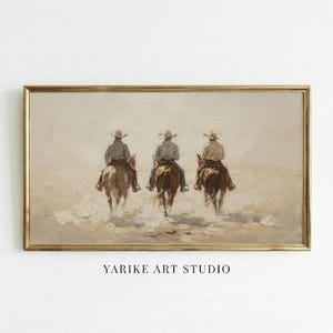 Könnte beinhalten: Gerahmtes Kunstwerk mit drei Cowboys auf Pferden, von hinten gesehen, die durch eine staubige Landschaft reiten. Das Gemälde hat eine Vintage-Ästhetik mit einer neutralen Farbpalette und einem goldfarbenen Rahmen. Der Text "YARIKE ART STUDIO" befindet sich unten.