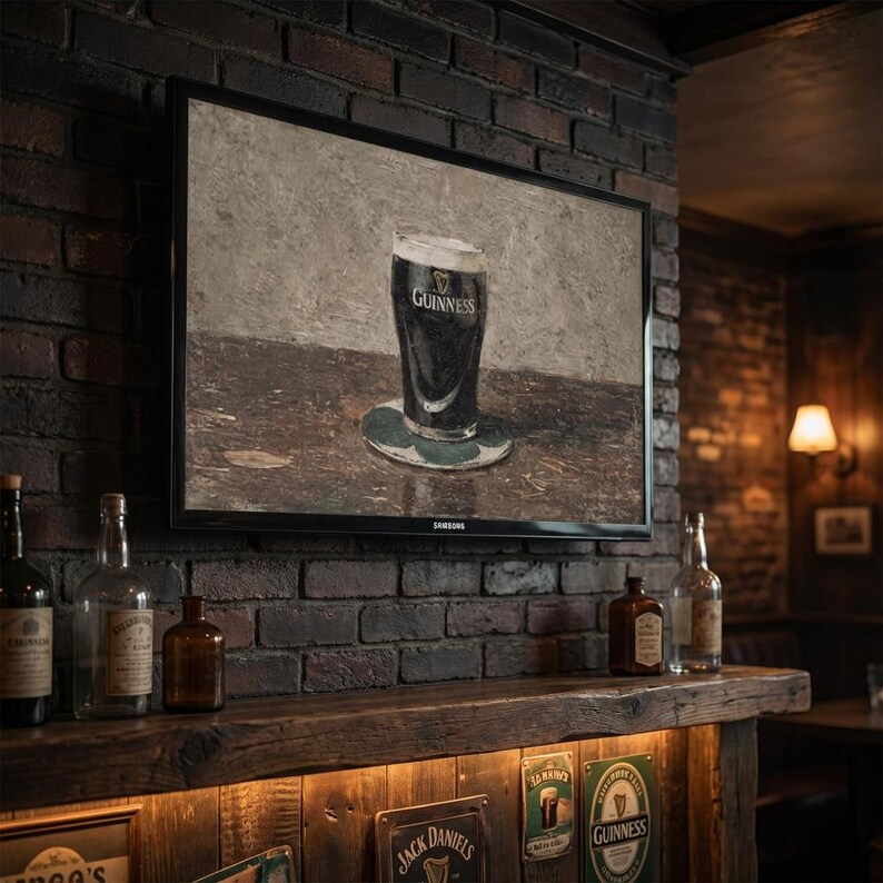 May include: A framed painting of a pint of Guinness stout on a coaster, displayed on a brick wall. The painting is above a wooden bar with bottles and vintage signs. The TV is a Samsung.