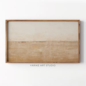 May include: Abstract landscape painting in a wooden frame with a light brown and beige color scheme. The painting features a horizontal line dividing the canvas into two sections, with the top section being a lighter beige and the bottom section being a darker brown. The painting is signed "YARIKE ART STUDIO" in the bottom center.