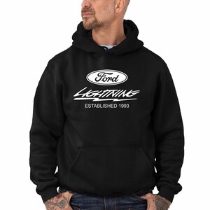 Puede incluir: Sudadera con capucha negra con un logotipo blanco de Ford Lightning y el texto "Establecido en 1993".