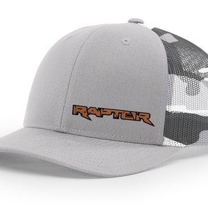 May include: A gray and white camouflage trucker hat with a gray front panel and a brown embroidered logo that says "RAPTEIR".