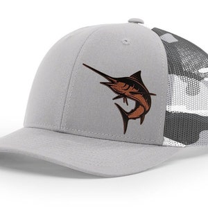 May include: A gray and black camouflage trucker hat with a brown marlin fish graphic on the front.