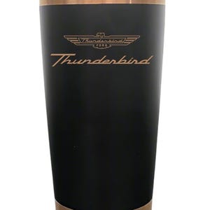 Puede incluir: Un vaso de acero inoxidable negro mate con borde y base de color cobre. La parte frontal muestra el logotipo de Ford Thunderbird y la palabra Thunderbird en una fuente cursiva de color cobre. El vaso incluye una tapa de plástico transparente.