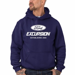Puede incluir: Una sudadera con capucha azul marino con un logotipo blanco de Ford Excursion y el texto "Establecido en 2000".