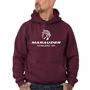Puede incluir: Una sudadera con capucha color burdeos con un logotipo blanco que dice "Marauder Established 1963". El logotipo presenta una imagen estilizada de una persona con casco.