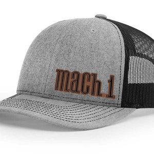 May include: A gray and black trucker hat with a brown leather patch that says "mach 1".