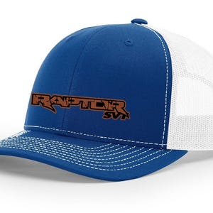 May include: A blue and white trucker hat with a brown embroidered logo that says "RAPTOR SVT".