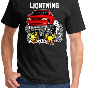 May include: A black t-shirt with a red Ford Lightning pickup truck graphic. The truck is depicted with flames coming out of the exhaust pipes and the words "LIGHTNING" are printed above the truck.
