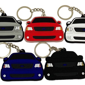 May include: Five Ford F-150 keychains in different colors: silver, red, white, blue, and black. Each keychain features a detailed front-end design of the truck.