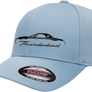 Puede incluir: Una gorra de béisbol azul claro con una silueta negra de un Ford Thunderbird y el texto "Thunderbird" bordado en la parte delantera. La gorra tiene una etiqueta Flexfit en la parte posterior.