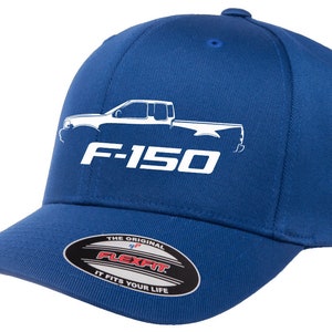 Può includere: Un berretto da baseball blu reale con un contorno bianco di un camion Ford F-150 e il testo "F-150" in bianco. Il berretto ha un'etichetta Flexfit bianca con il testo "The Original Flexfit It Fits Your Life".