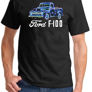 May include: A black t-shirt featuring a blue and white graphic of a vintage Ford F-100 pickup truck. The text "Ford F-100" is printed below the truck.