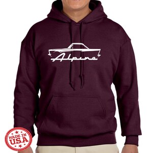 May include: Burgundy hooded sweatshirt with a white silhouette of a classic car and the word "Alpine" printed on the front. The sweatshirt has a kangaroo pocket and a drawstring hood.