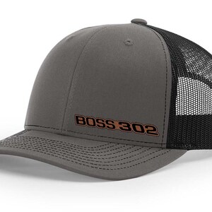 May include: A gray and black trucker hat with a brown embroidered logo that says "BOSS 302".