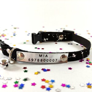 May include: Black cat collar with a silver name tag that reads "MIA 6978800007" and a silver bell. The collar has a white star pattern on a black background.