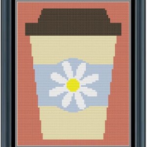 May include: Cross-stitch artwork of a coffee cup with a daisy design. The cup is light yellow with a blue band featuring a white daisy with a yellow centre. The lid is brown, and the background is peach-coloured, all within a black frame.