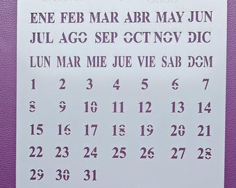 May include: White plastic calendar stencil with the months of the year and days of the week in Spanish. The numbers 1 through 31 are printed on the stencil.