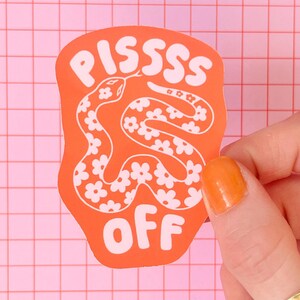 Peut inclure: Un autocollant découpé avec un fond orange représentant un serpent blanc orné de petites fleurs. Le texte PISSSS est imprimé en blanc au-dessus du serpent, et le mot OFF est imprimé en blanc sous le serpent dans une police grasse et arrondie.