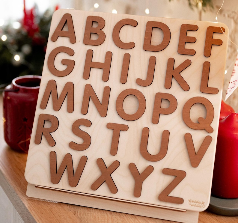 Op de afbeelding: Houten alfabetpuzzel met hoofdletters A tot en met Z in bruin op een lichte houten achtergrond.