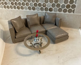 Casa de muñecas en miniatura. Juego de sofá seccional moderno de 5 piezas en imitación de cuero con otomana y mesa de centro redonda. Escala 1:12.
