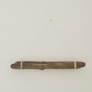 May include: A piece of driftwood is hanging from the ceiling with twine. The driftwood is brown and has a natural, rough texture.