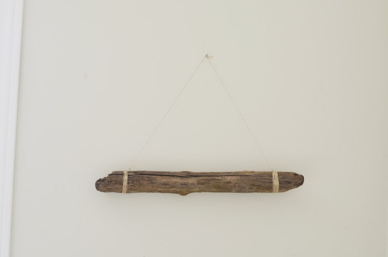 May include: A piece of driftwood is hanging from the ceiling with twine. The driftwood is brown and has a natural, rough texture.