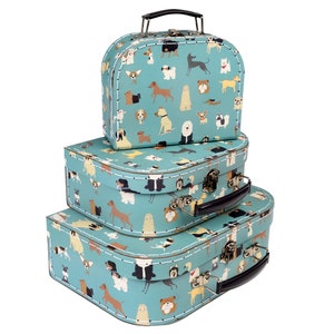 May include: Three blue and white suitcases with a dog pattern. The suitcases are stacked on top of each other, with the largest suitcase at the bottom and the smallest suitcase at the top.