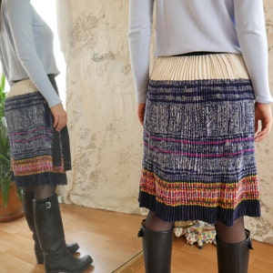 May include: A pleated skirt with a white, blue, pink, yellow, and red patterned design. The skirt is made of a lightweight fabric and has a relaxed fit.