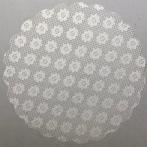 May include: White crocheted doily with a circular design featuring a repeating pattern of small flowers.
