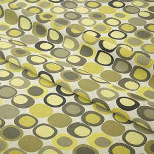 May include: A fabric with a repeating pattern of yellow, green, and black circles on a white background.